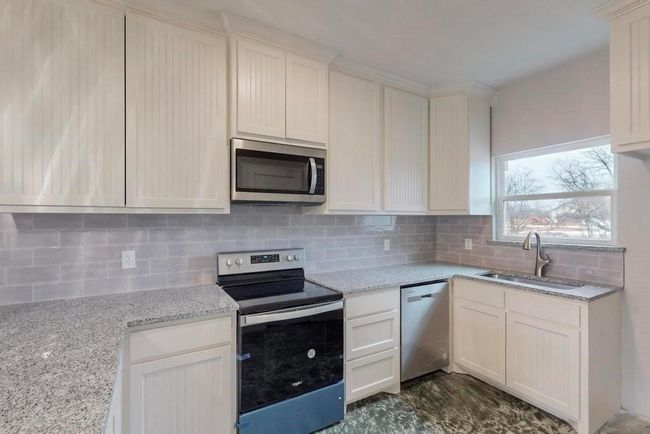 Kitchen featuring tasteful backsplash, appliances with stainless steel finishes, a sink, and light stone counters | Image 8