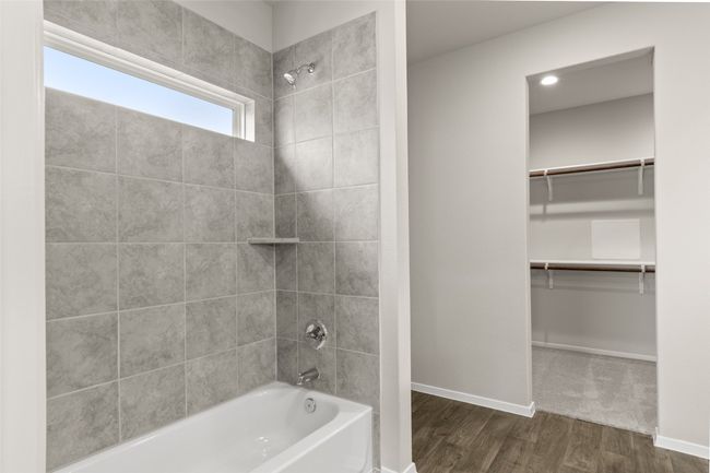 Full bath with a spacious closet, bathing tub / shower combination, baseboards, and wood finished floors | Image 20