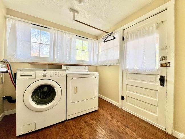 Clothes washing area featuring wood finished floors, a textured ceiling, washing machine and dryer, baseboards, and laundry area | Image 25