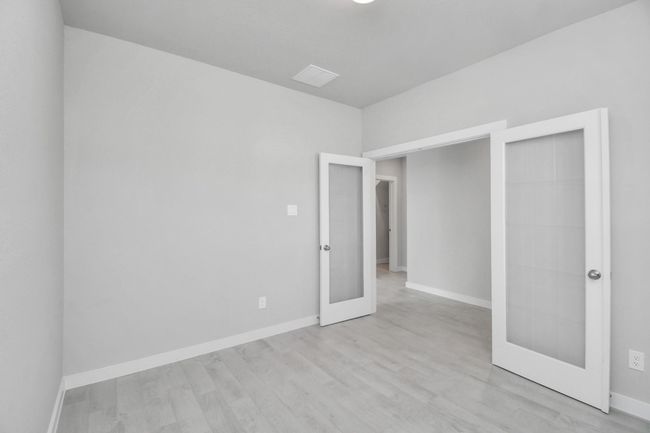 Experience the perfect blend of sophistication and warmth in this home office, boasting elegant wood-look tile flooring and flooded with natural light from expansive windows and French doors. | Image 6
