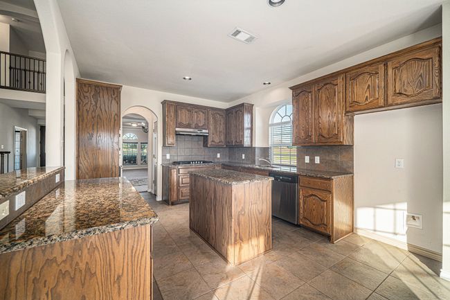 Kitchen with dishwasher, arched walkways, a kitchen island, tasteful backsplash, and gas cooktop | Image 9