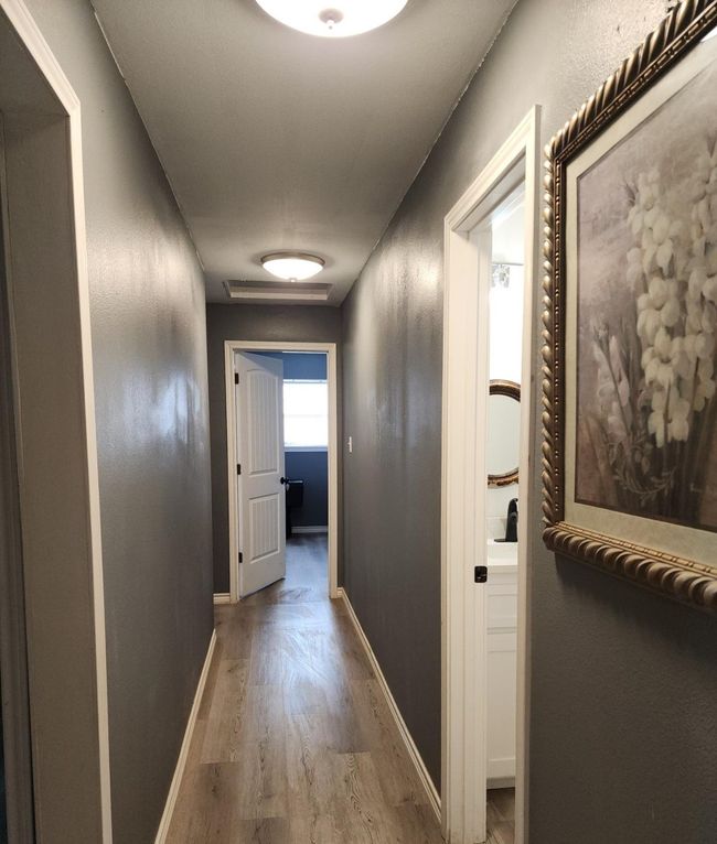 hallway leading to 3 bedrooms with baseboards and wood laminate floors | Image 6