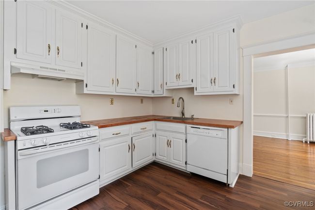 Kitchen featuring white appliances, a sink, under cabinet range hood, and wood floors | Image 20