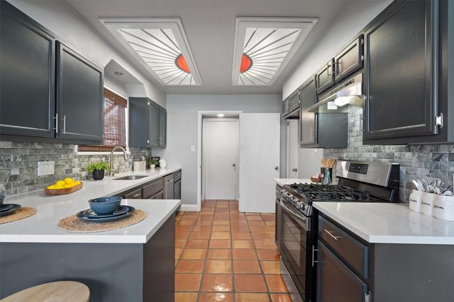 Kitchen featuring stainless steel appliances, tasteful backsplash, under cabinet range hood, light countertops, and a peninsula | Image 11
