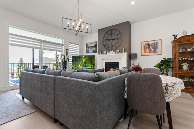 Living area with a chandelier, a glass covered fireplace, light wood-style floors, and recessed lighting | Image 4