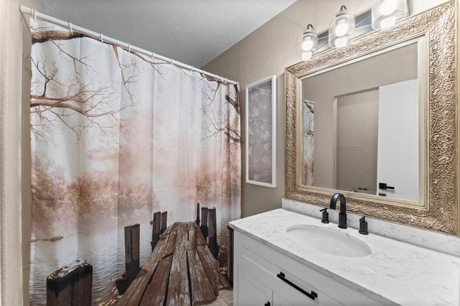 This bathroom features a vanity with a marble countertop, a large ornate mirror with modern light fixtures. | Image 24
