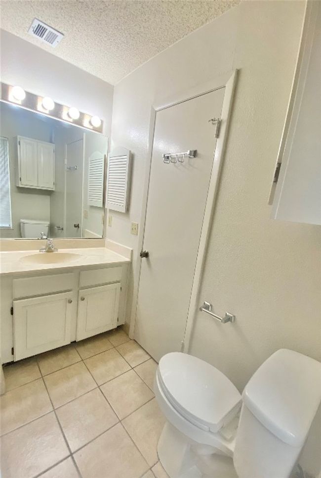 Bathroom with tile patterned floors, a textured ceiling, visible vents, and toilet | Image 11