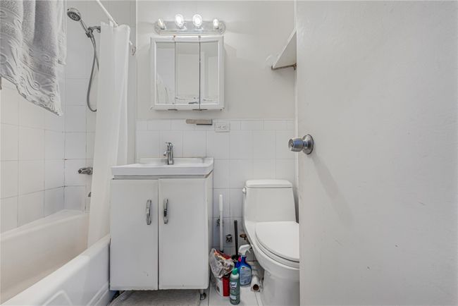 Bathroom featuring vanity, shower / tub combo, tile walls, tile patterned flooring, and a wainscoted wall | Image 18