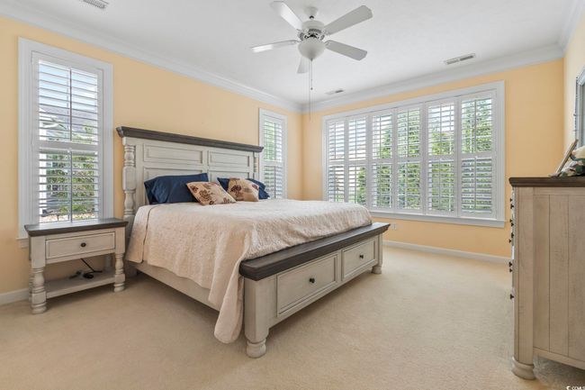 Bedroom with crown molding, visible vents, light carpet, and baseboards | Image 13