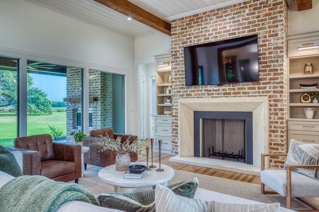 Charming reclaimed brick fireplace with an elegant custom-carved stone mantle. | Image 7