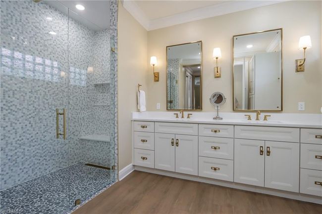 Bathroom featuring a stall shower, crown molding, double vanity, and wood finished floors | Image 11