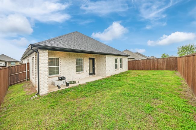 Rear view of property featuring a patio area, a fenced backyard, a lawn, and roof with shingles | Image 32