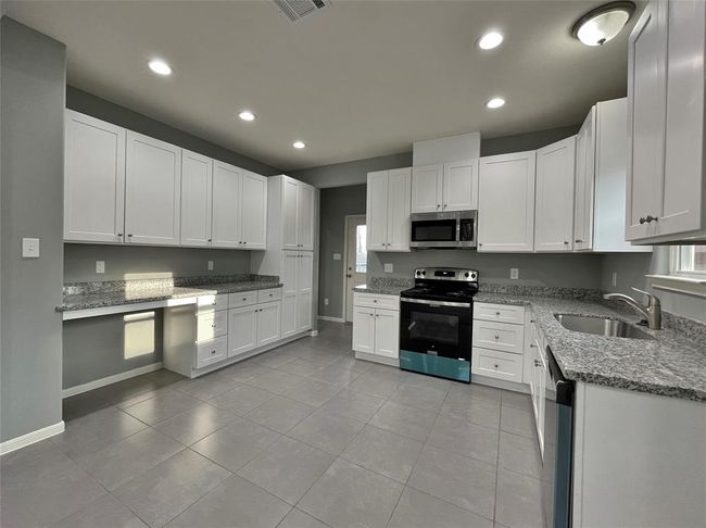 The kitchen offers ample storage and counter space as well as natural light, creating a bright and functional cooking area. | Image 4