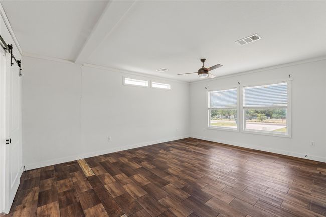 Unfurnished room with a barn door, healthy amount of natural light, dark wood-type flooring, ornamental molding, and a ceiling fan | Image 13