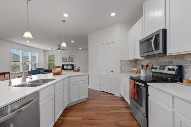 Kitchen with stainless steel appliances, dark wood-style floors, tasteful backsplash, light countertops, and recessed lighting | Image 11