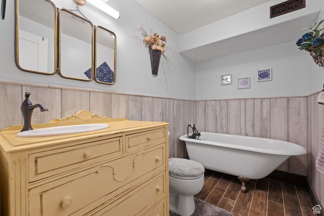 Full bathroom with a freestanding tub, toilet, vanity, wainscoting, and wood finish floors | Image 27