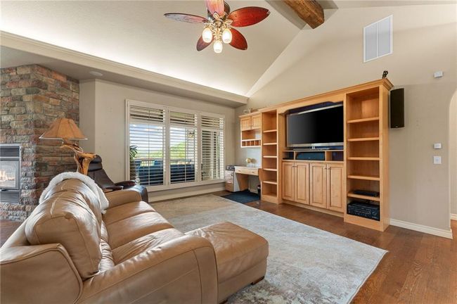 Living room with visible vents, baseboards, beam ceiling, dark wood finished floors, and a ceiling fan | Image 12