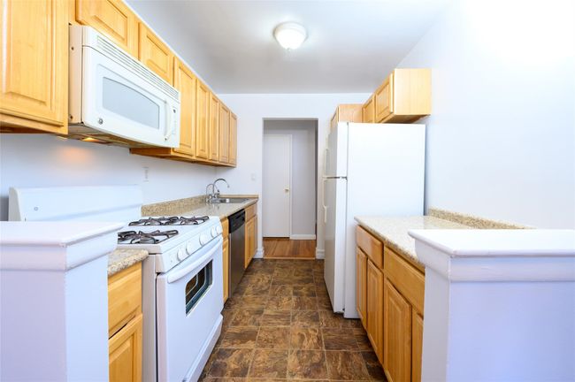 Kitchen featuring white appliances, light brown cabinetry, and sink | Image 6