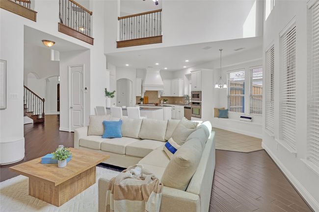 Living area with arched walkways, a high ceiling, wood finished floors, and stairs | Image 8