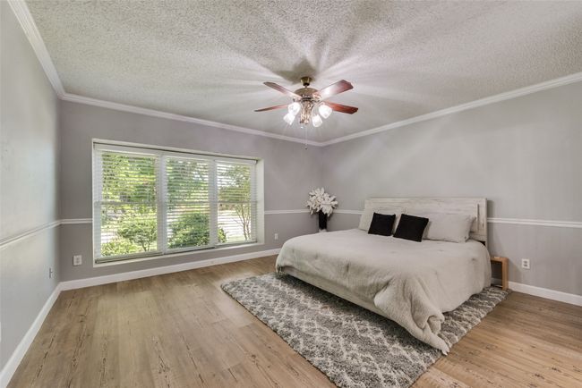 Bedroom featuring a textured ceiling, wood finished floors, ornamental molding, and ceiling fan | Image 16