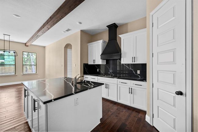 Kitchen with a sink, visible vents, custom exhaust hood, beamed ceiling, and dark countertops | Image 28