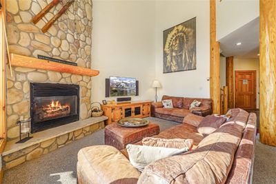 Vaulted living room featuring a beautiful rock fireplace | Image 2