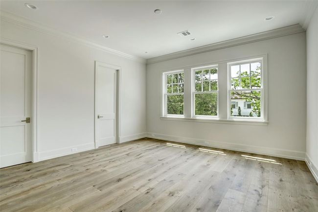 One of five generously sized secondary bedrooms, this light-filled space features soaring ceilings, expansive windows, a walk-in closet with built-in hanging storage, and elegant white oak hardwood floors. | Image 26