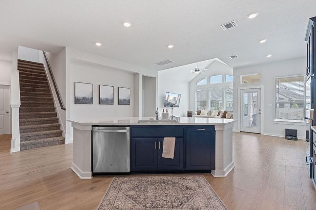 Kitchen with light countertops, visible vents, stainless steel dishwasher, and a sink | Image 12