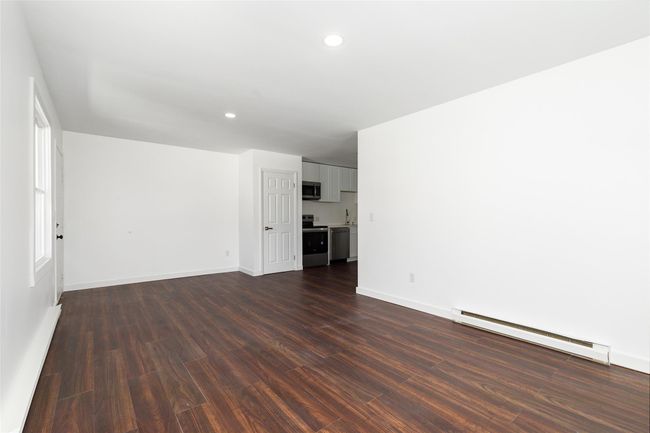 Unfurnished living space featuring baseboards, baseboard heating, dark wood finished floors, and recessed lighting | Image 5