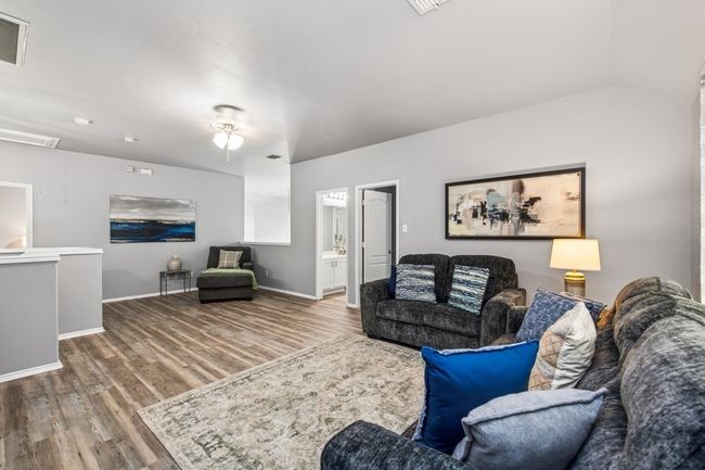 Living room featuring baseboards, vaulted ceiling, attic access, visible vents, and wood finished floors | Image 31