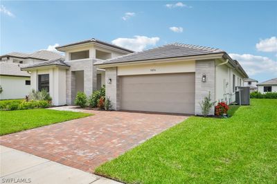 Prairie-style home with a garage, a front lawn, and central AC unit | Image 2