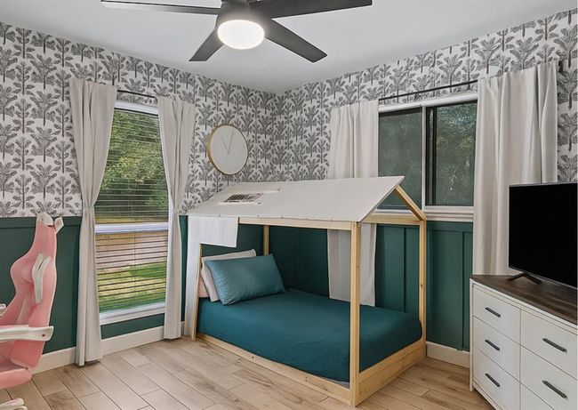 Whimsical kid’s room with playful wallpaper, custom house-frame bed, and natural light. | Image 31
