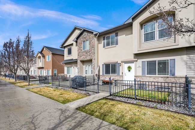 Townhome / multi-family property featuring stucco siding, stone siding, a residential view, and a fenced front yard | Image 5
