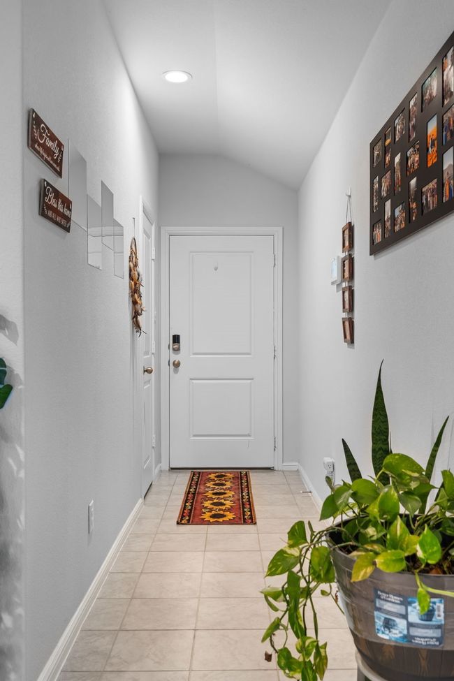 Doorway with light tile patterned floors, baseboards, and vaulted ceiling | Image 4