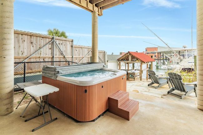 This outdoor space features a private hot tub, patio seating, and a view of the marina, perfect for relaxation and entertaining. | Image 34