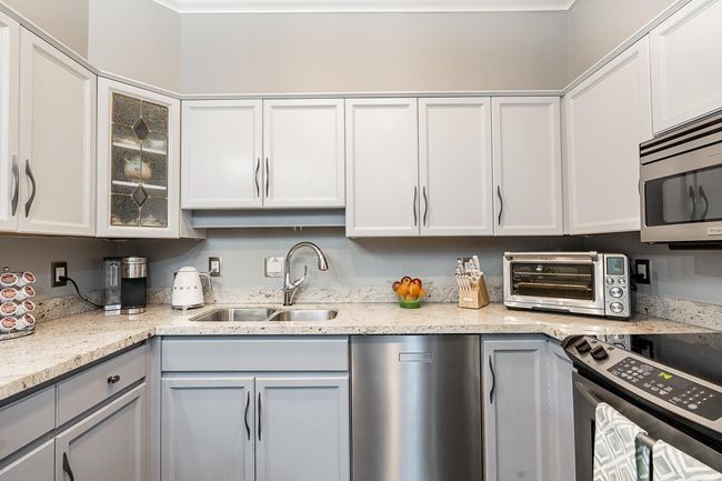 Kitchen with gray cabinetry, a sink, appliances with stainless steel finishes, a toaster, and glass insert cabinets | Image 4