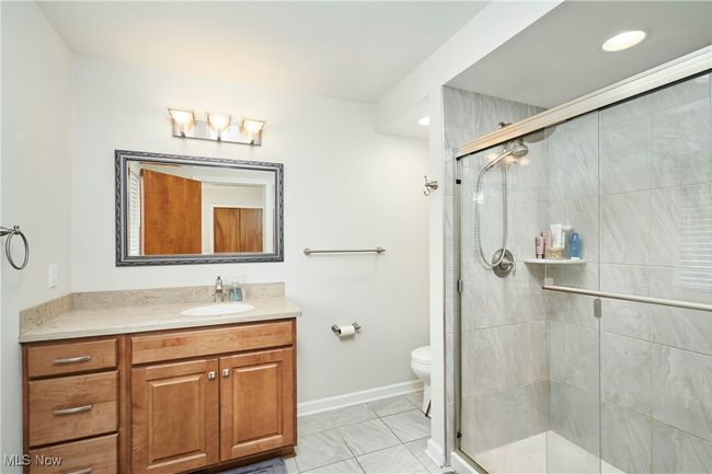 Bathroom featuring a shower stall, vanity, toilet, baseboards, and marble look tile flooring | Image 18
