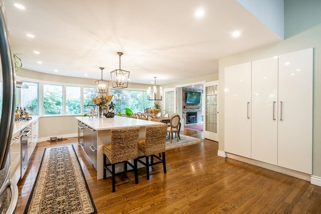 Dining area with dark wood-style floors, recessed lighting, a chandelier, and a stone fireplace | Image 9