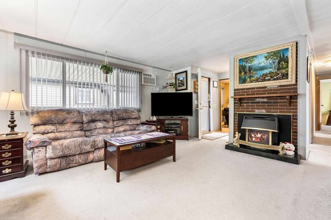 Carpeted living area with a fireplace and an AC wall unit | Image 8
