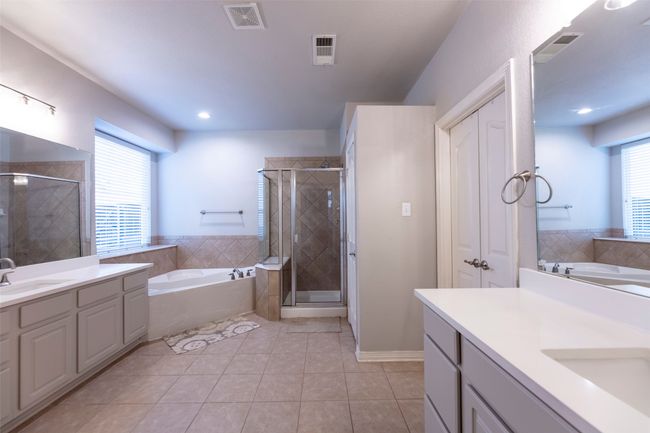 Bathroom featuring two vanities, a garden tub, plenty of natural light, and recessed lighting | Image 21