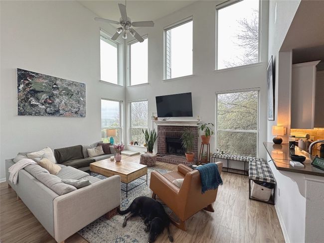 Living area with light wood-type flooring, ceiling fan, plenty of natural light, and a towering ceiling | Image 7