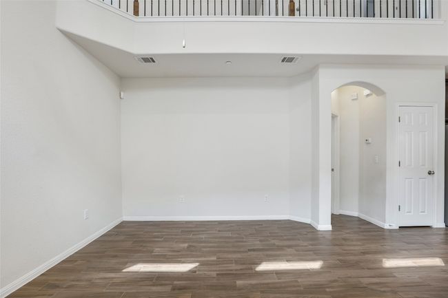 Spare room featuring arched walkways, wood finished floors, visible vents, and a high ceiling | Image 14