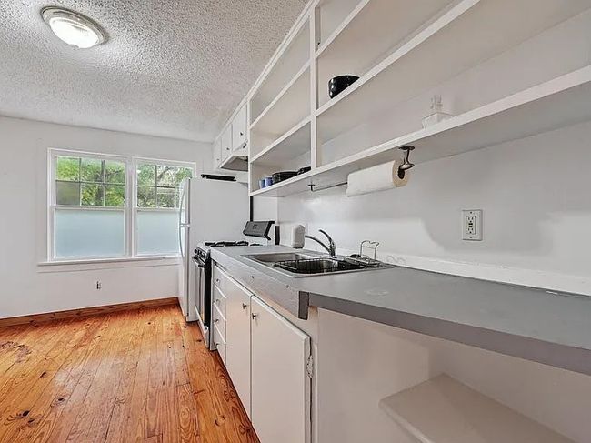Kitchen with stove, open shelves, a textured ceiling, white cabinetry, and light wood-style floors | Image 4
