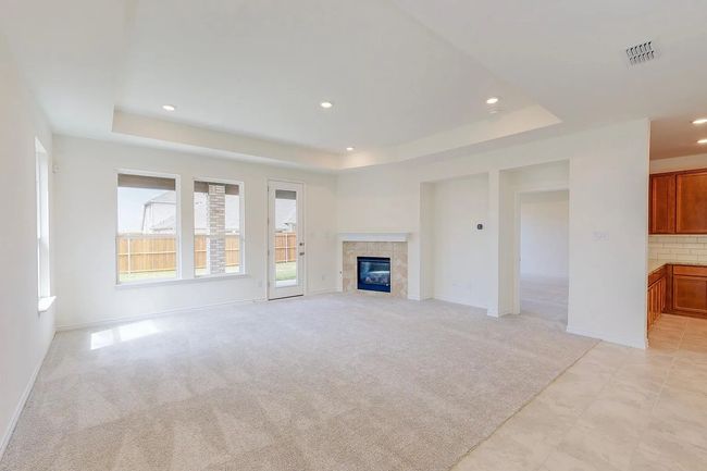 Unfurnished living room featuring a tray ceiling, recessed lighting, baseboards, a fireplace, and light colored carpet | Image 11