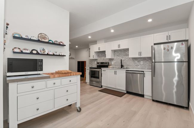 Kitchen with stainless steel appliances, white cabinetry, light wood-type flooring, tasteful backsplash, and recessed lighting | Image 28