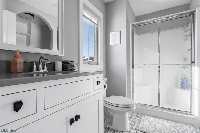 Bathroom with tile floors, toilet, double vanity, and an enclosed shower | Image 24