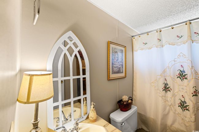 Full bath featuring a textured ceiling, a shower with shower curtain, and vanity | Image 8