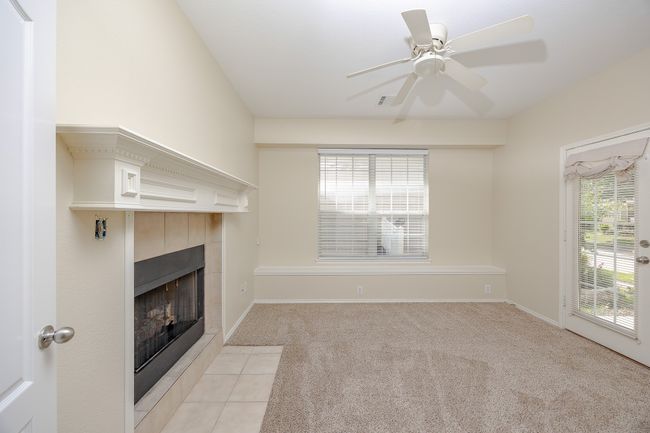 living room with a tile fireplace, light colored carpet, and a ceiling fan | Image 6