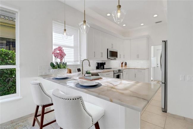 Kitchen with a peninsula, a kitchen bar, white cabinets, tasteful backsplash, and stainless steel appliances | Image 11