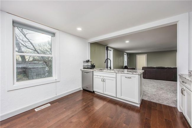Kitchen with visible vents, a sink, stainless steel dishwasher, open floor plan, and a peninsula | Image 39
